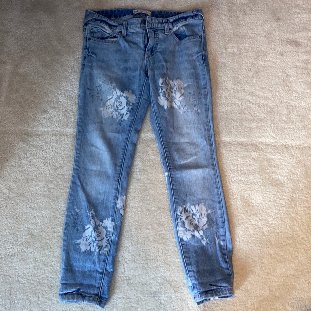 Free People stretch skinny jeans with a bleached, white flower pattern.